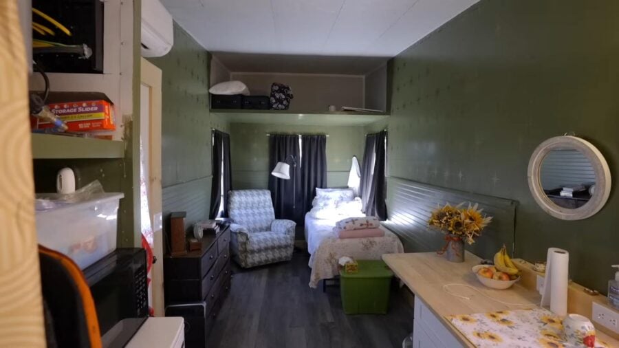 Compact tiny house bedroom with cozy bed and seating area.