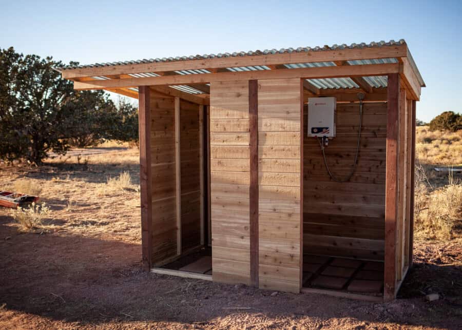 A-frame tiny house with outdoor shower in desert landscape.