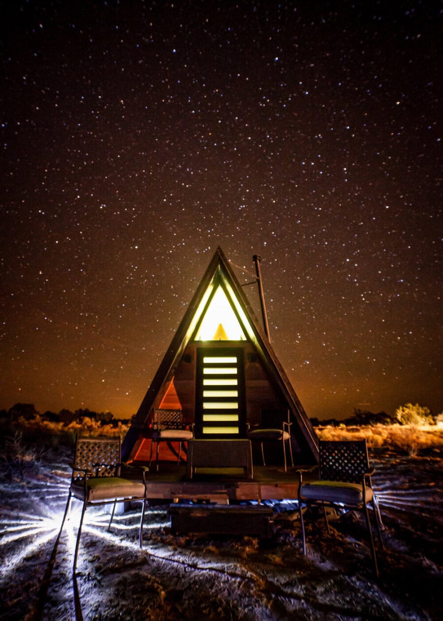 A-frame tiny house illuminated at night near the Grand Canyon.