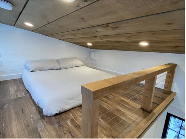 Compact tiny house bedroom with a loft and minimalist design.