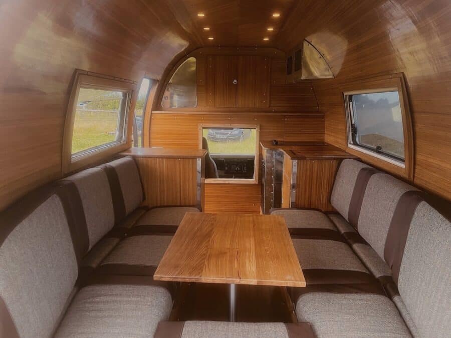 Interior of a classic Land Rover motorhome featuring wooden paneling and comfortable seating for tra.