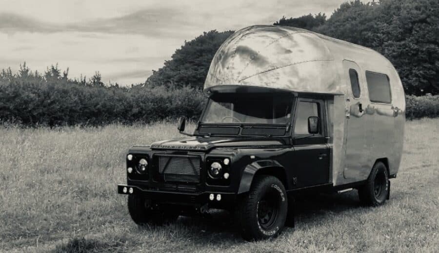 Land Rover-based motorhome parked outdoors in a grassy field.