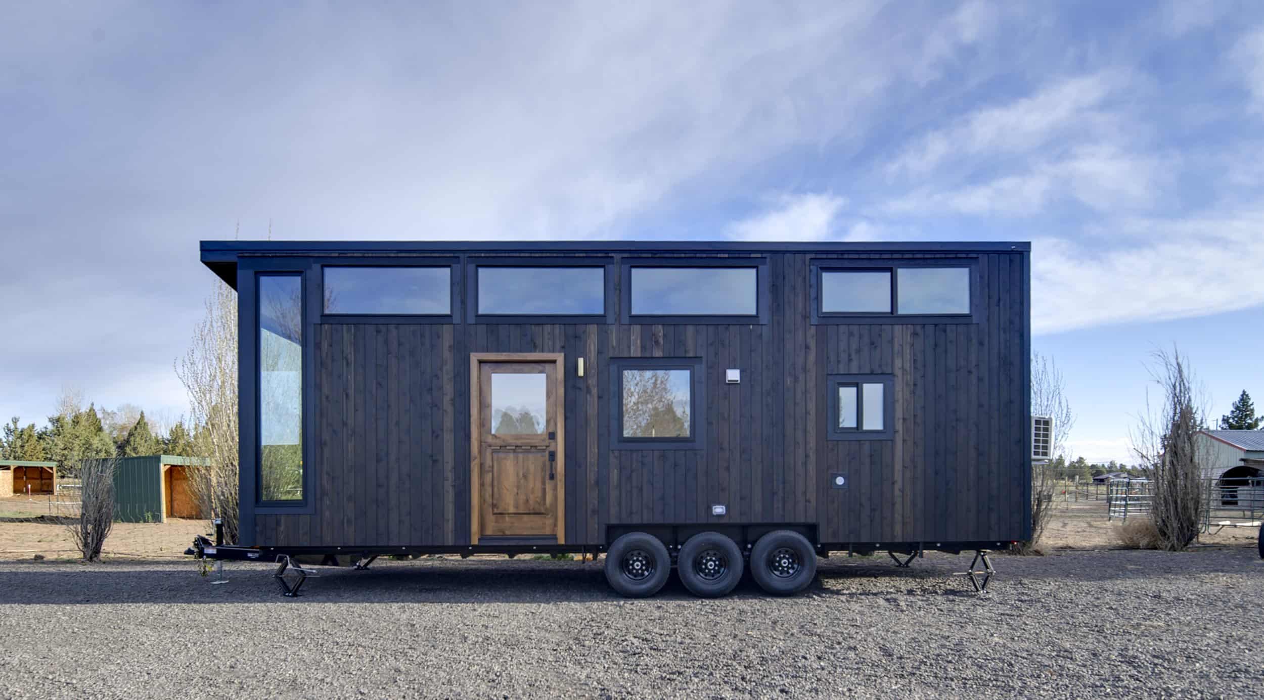 Side view of the Black Butte tiny house showing its charred wood siding, shed roof, and clerestory windows