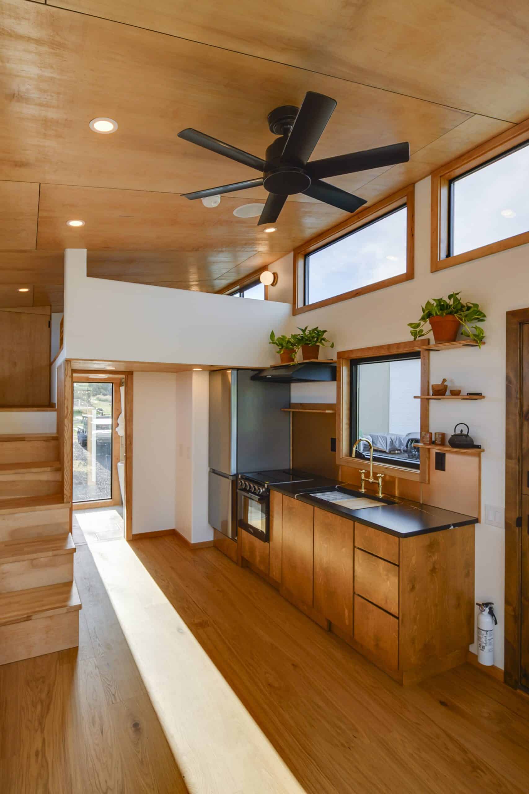 The Black Butte interior with plywood ceilings, honey oak floors, a storage staircase, and the kitchen beneath clerestory windows