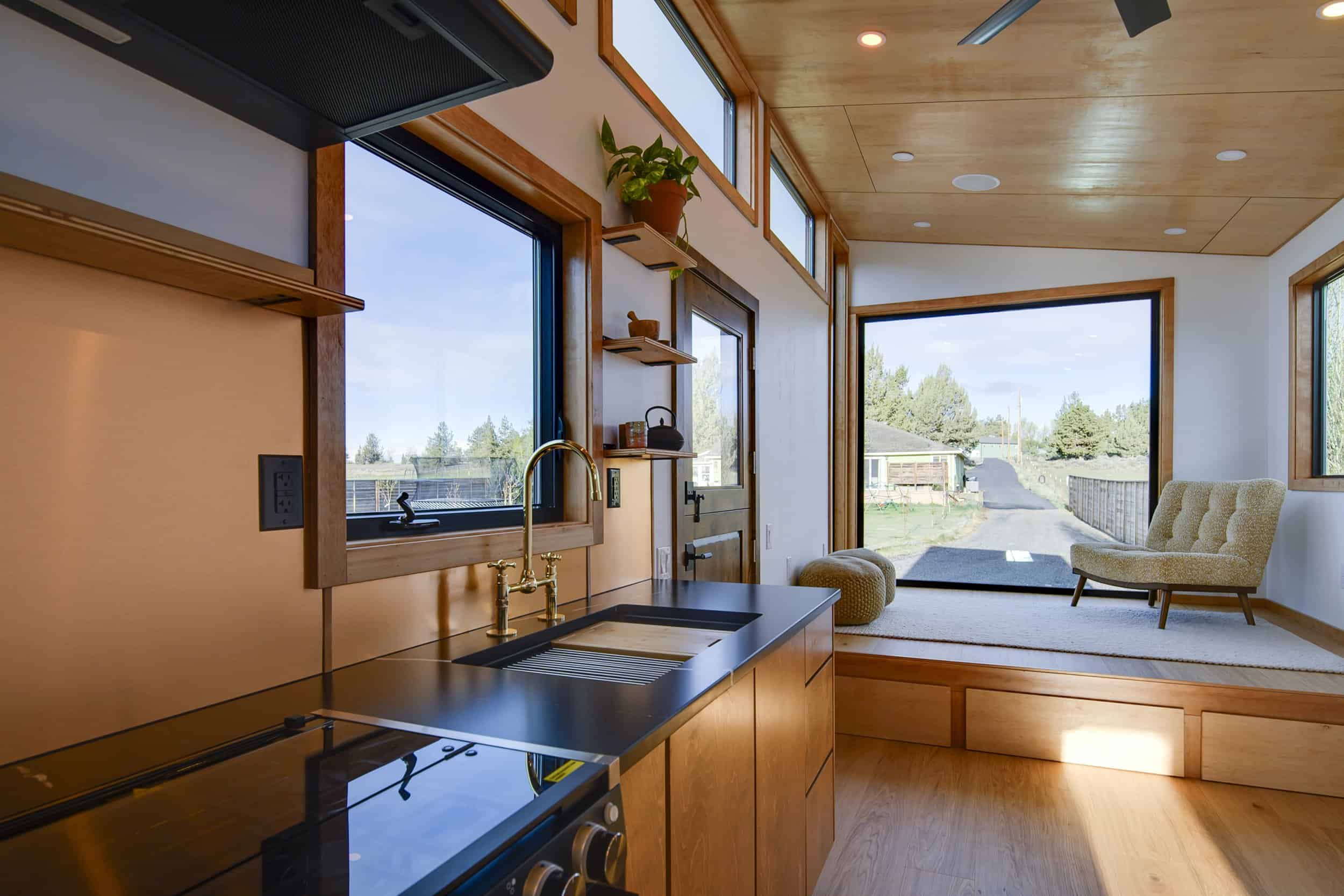 The Black Butte kitchen with black stone counters and brass fixtures looking toward the raised platform living room