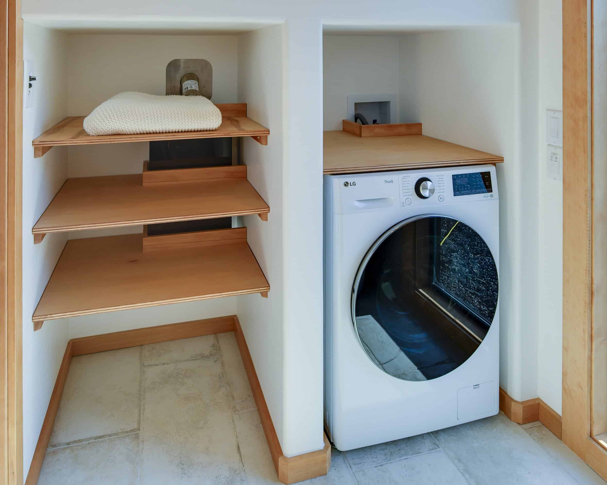 A full-size LG washer-dryer combo beside built-in Baltic birch shelving in the Black Butte tiny house