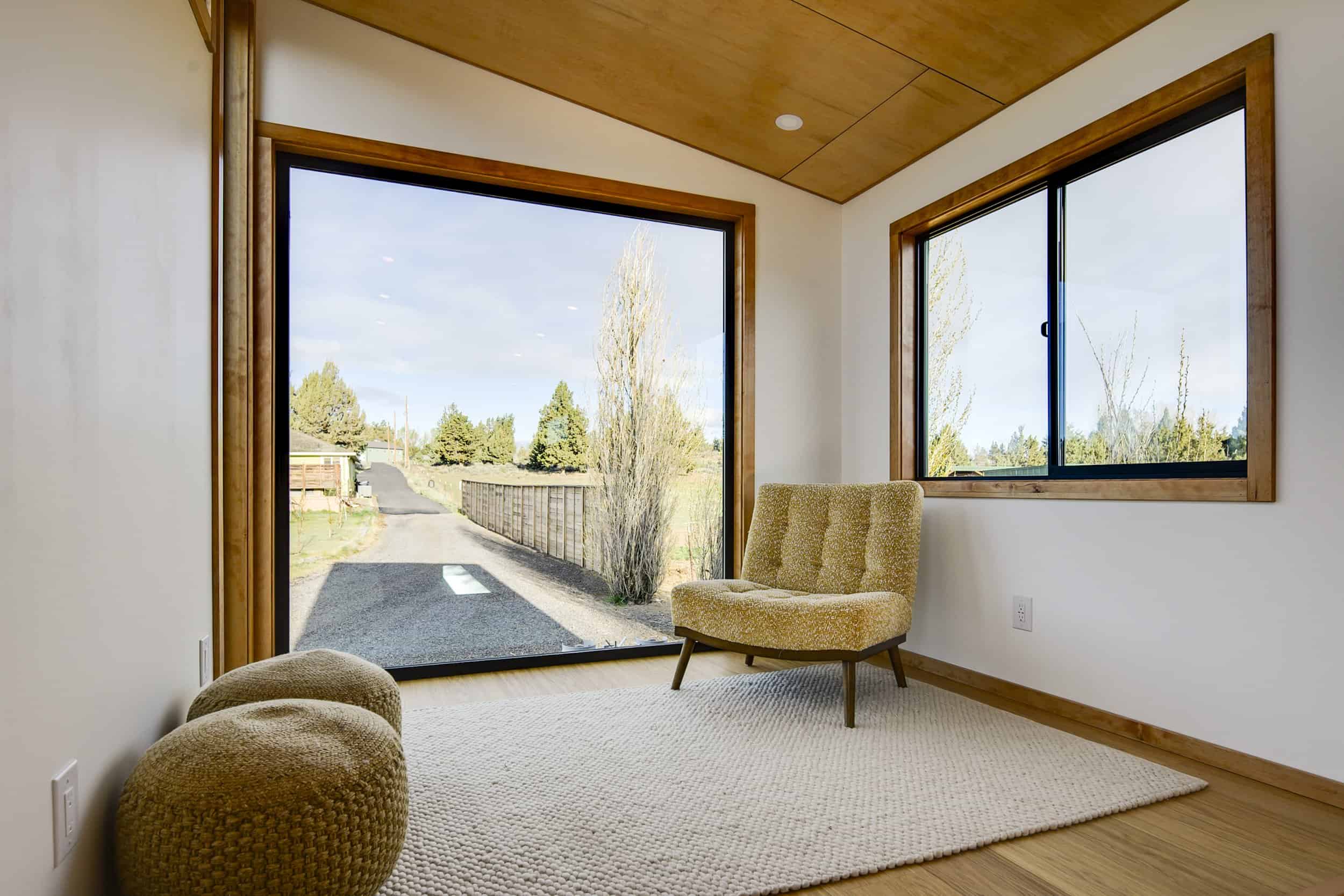 The Black Butte raised platform living room with a massive picture window, accent chair, and honey oak floors