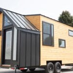 Black and pine tiny house on wheels with contemporary design and large windows.