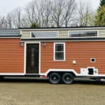Tiny house on wheels with modern exterior and large windows.