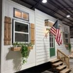 Compact tiny house with double lofts and charming exterior details.