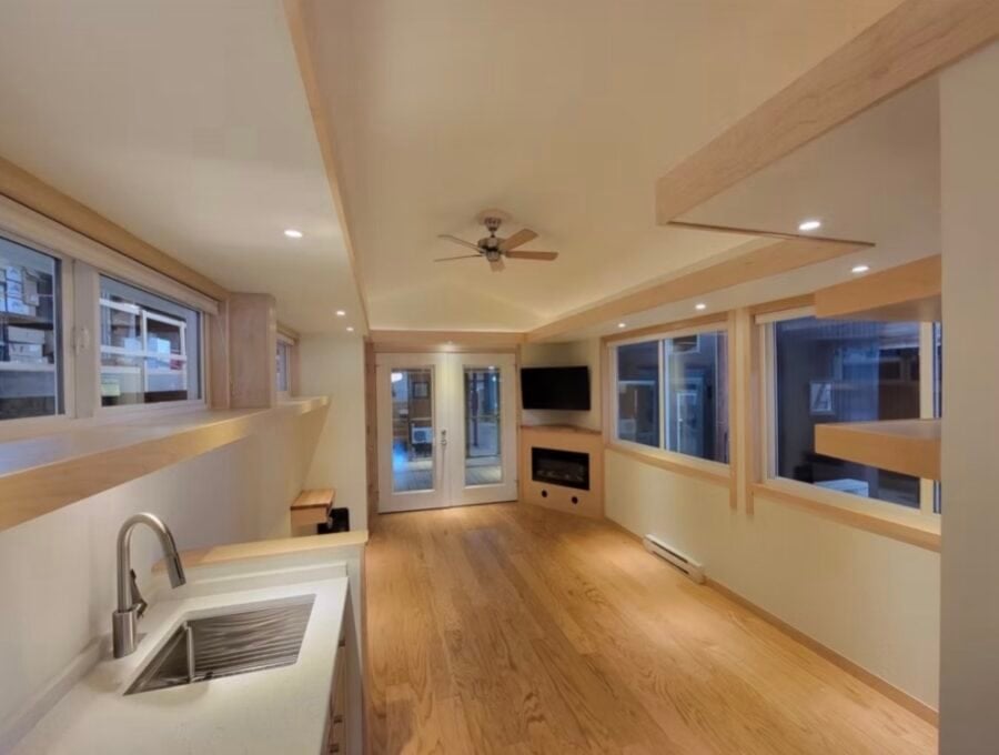 Bright and airy tiny house interior featuring large windows, hardwood floors, and a cozy living spac.