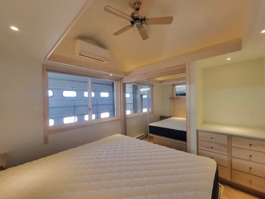 Interior view of a luxury tiny house bedroom featuring a spacious bed, ample natural light, and slee.