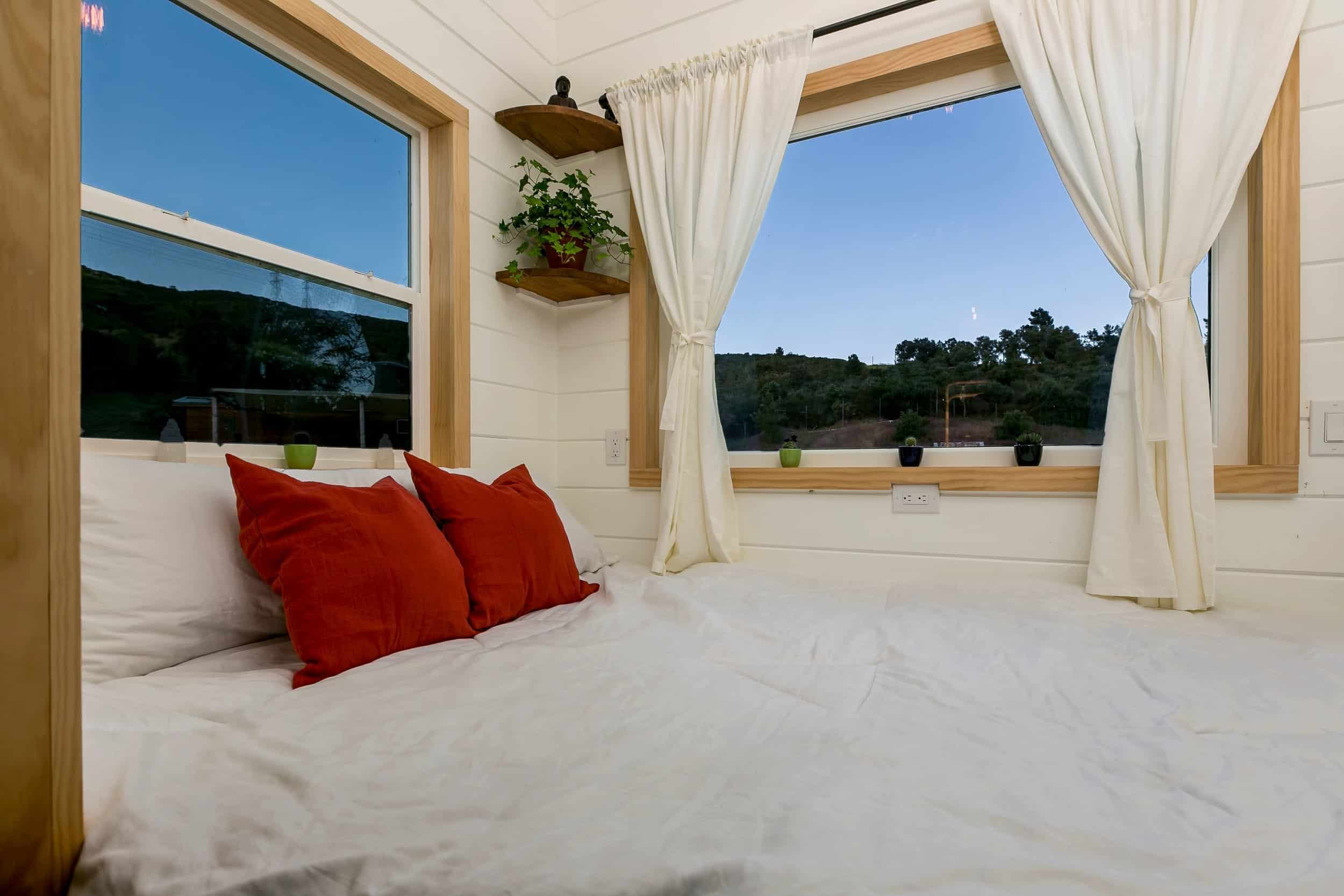 The Joshua Tree living room converted into a large bed with red pillows and corner windows