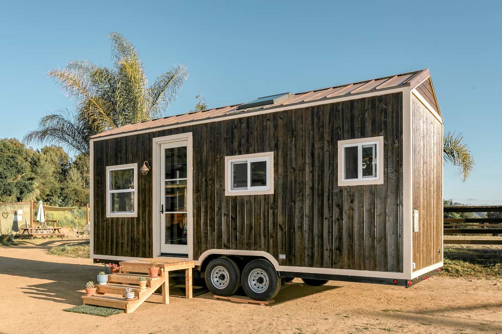 Side view of the Joshua Tree tiny house showing its weathered wood siding, windows, and metal roof