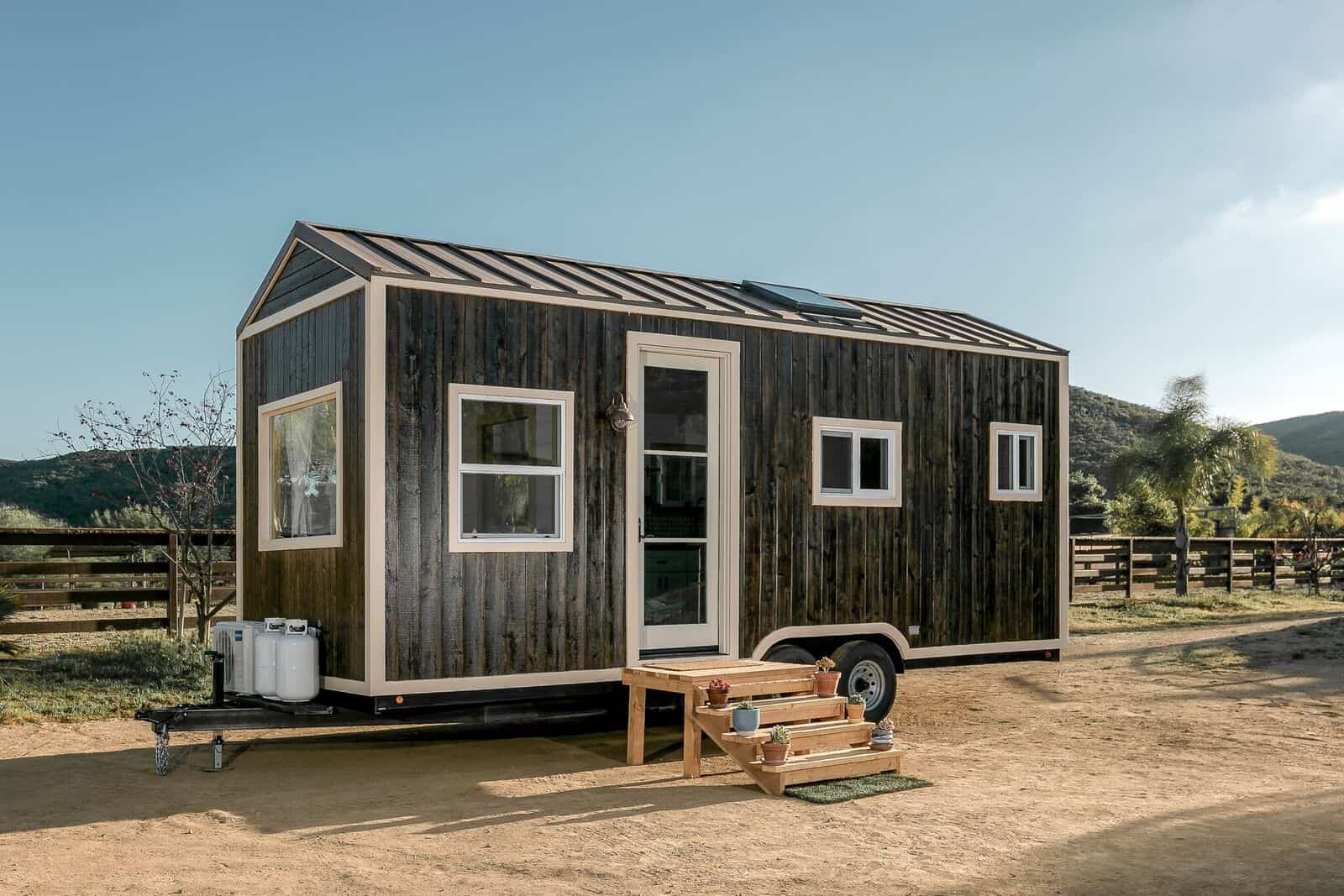The Joshua Tree tiny house by Spindrift Homes with weathered vertical wood siding and a metal roof on a double-axle trailer