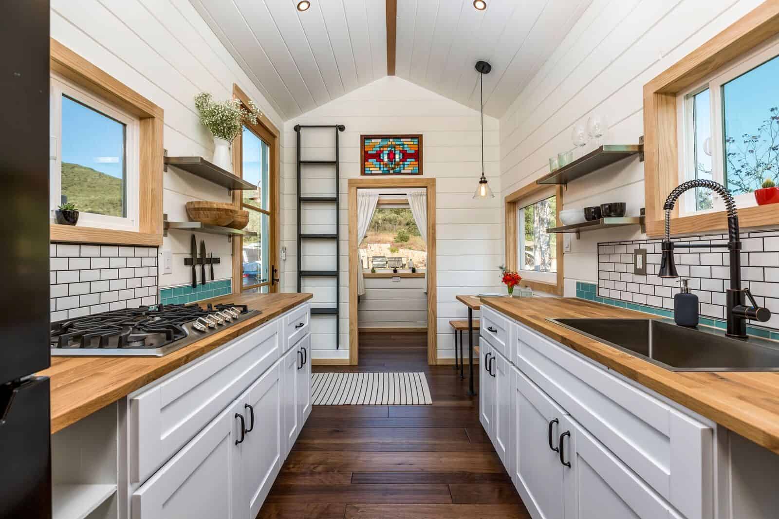 The Joshua Tree galley kitchen with butcher block counters, white cabinets, teal subway tile, and a stained-glass accent window over the doorway