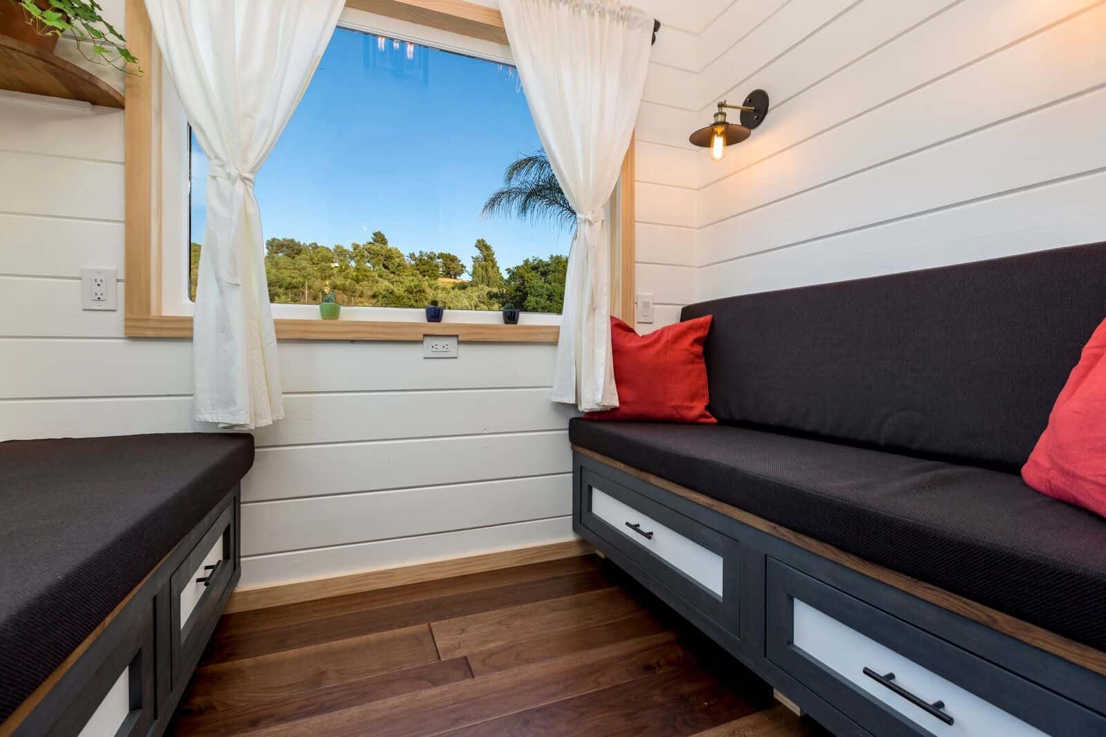 The Joshua Tree living room with two cushioned storage benches and red pillows beneath wraparound windows