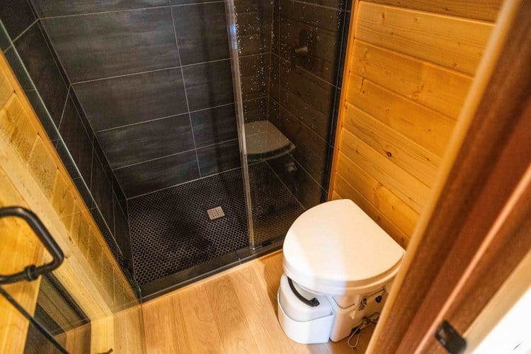 Compact bathroom in a tiny house with wooden accents and a modern shower.