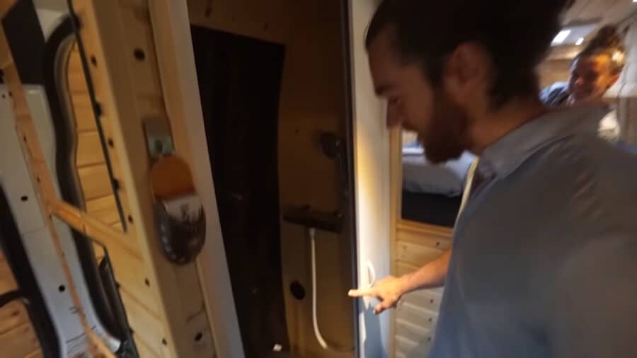 Interior of tiny house showing sliding bed, woodwork, and storage solutions.