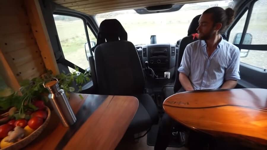 Van interior with beautiful woodwork and a sliding bed setup.