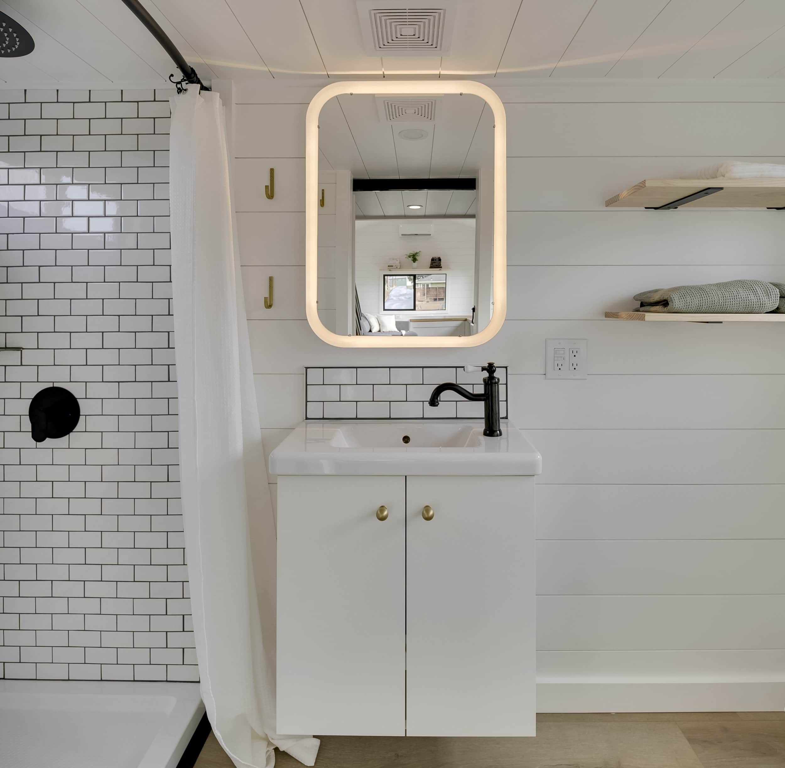 The Ochoco bathroom with a floating white vanity, vessel sink, backlit mirror, and subway tile