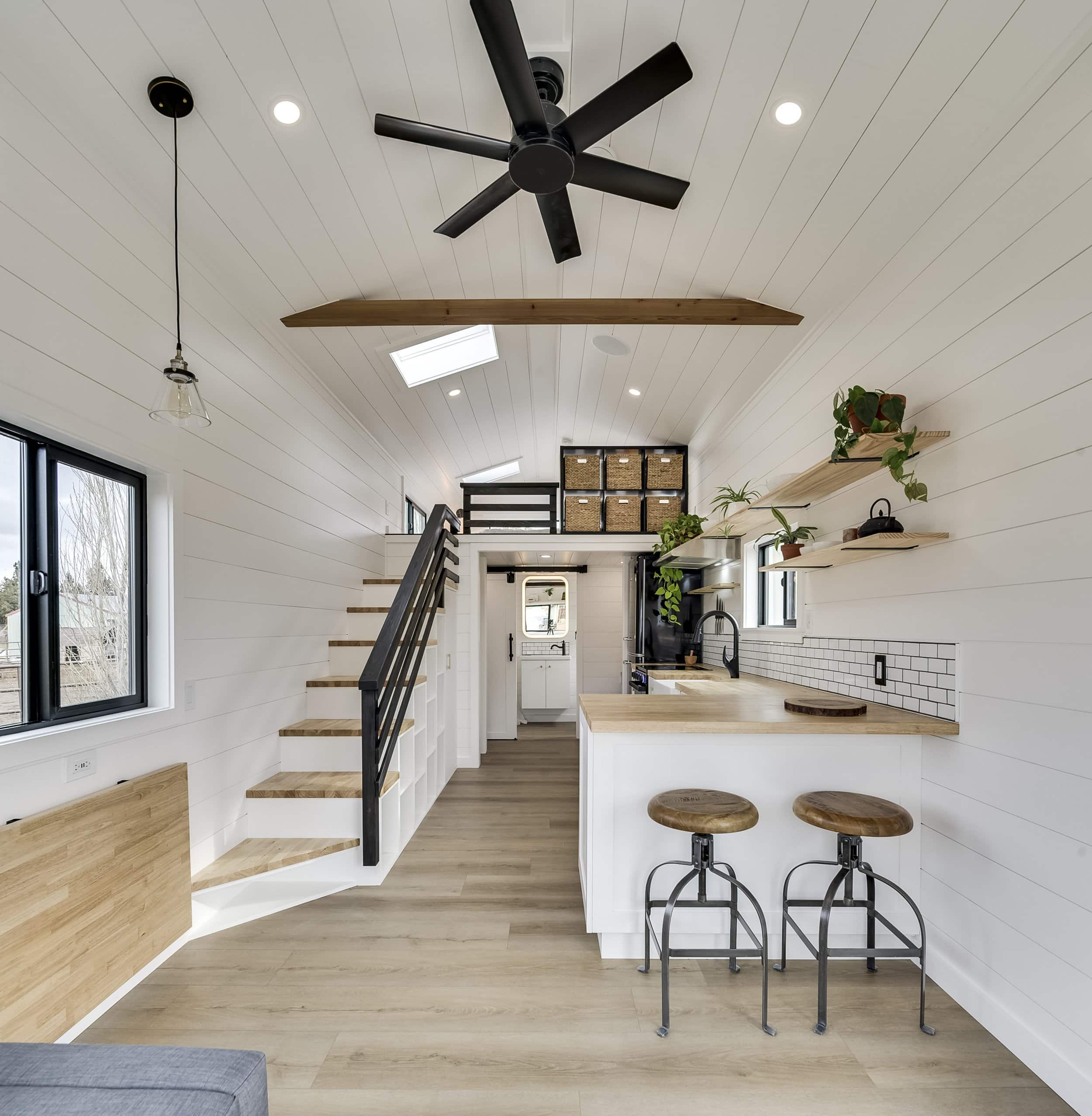 The Ochoco interior showing the open-tread staircase, peninsula kitchen with bar stools, and a loft above