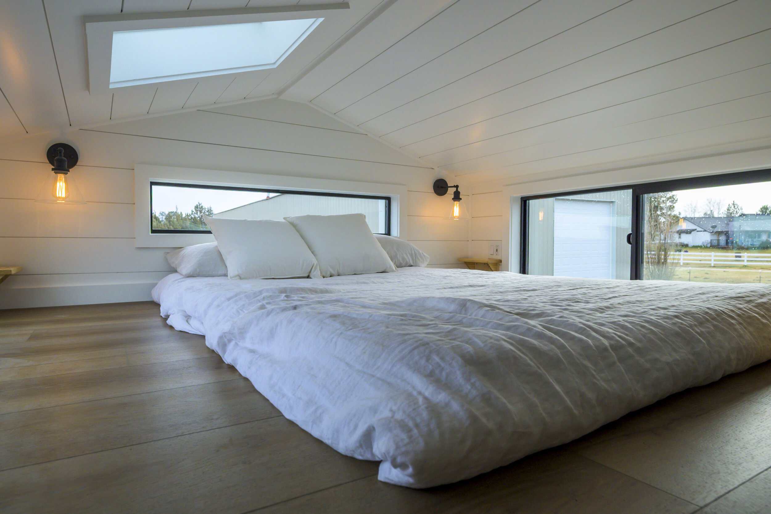 The Ochoco loft bedroom with a double bed, skylight, sliding glass door, and large windows