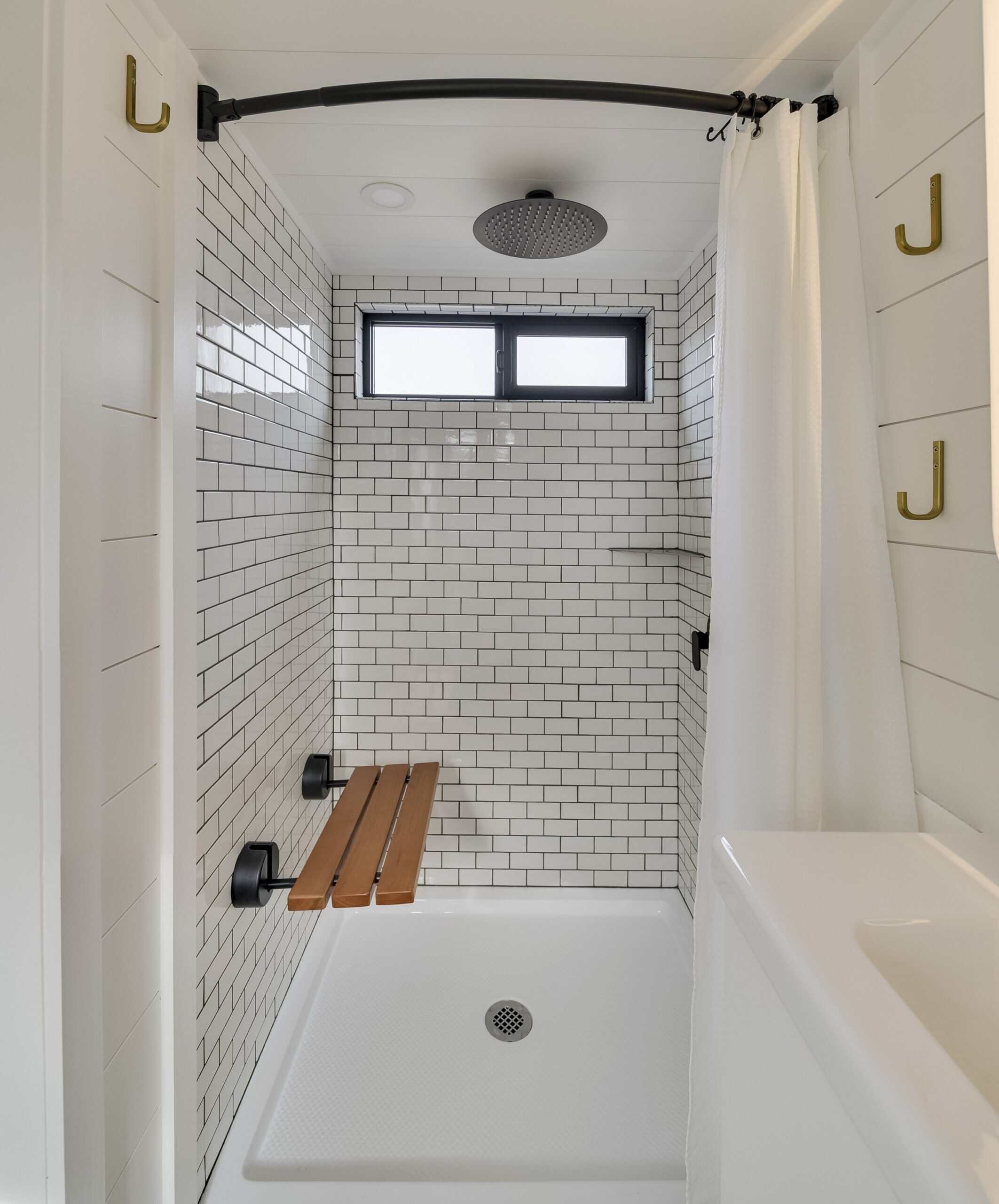 The Ochoco shower with white subway tile, a rainfall shower head, and a fold-down teak bench