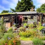 Off-grid tiny house surrounded by lush garden and greenery.