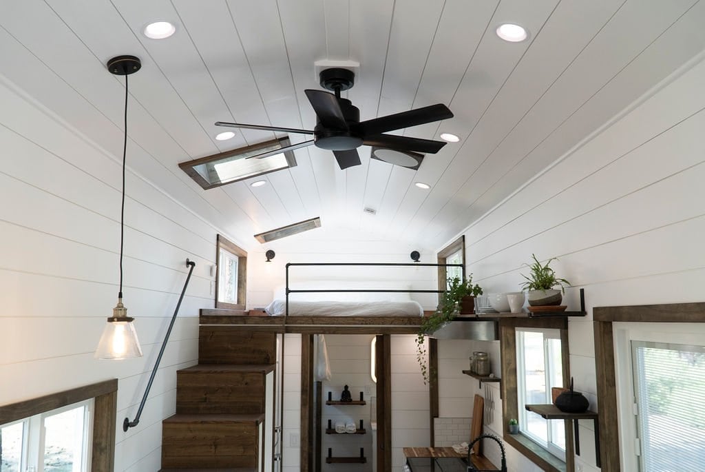 The Olympic sleeping loft with a pipe railing and skylights, viewed from across the vaulted living space
