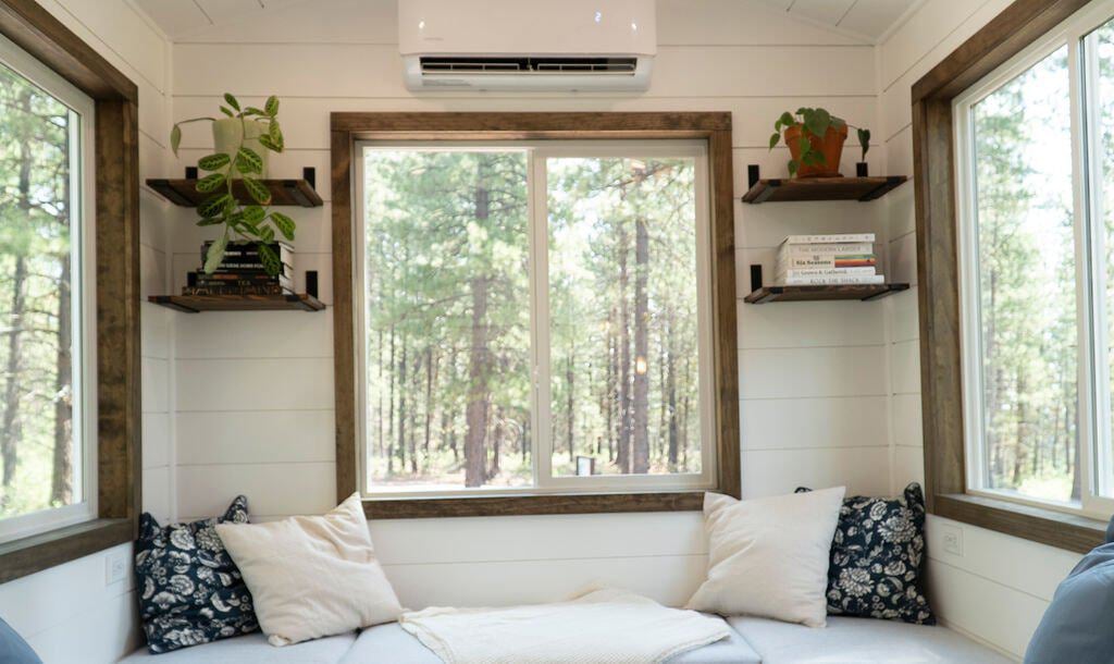 The Olympic sunken lounge with built-in bench seating, blue and white pillows, and large windows looking into the forest