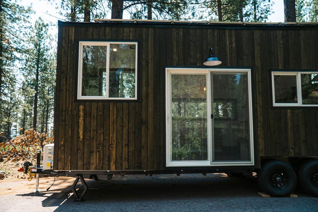 Close-up of the Olympic's white-framed sliding glass entry door set into dark wood siding on the trailer