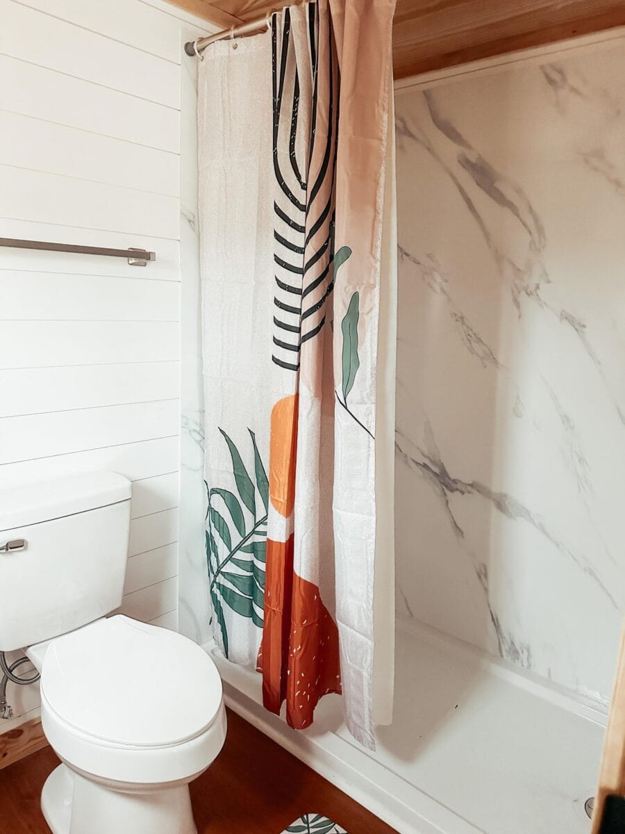 Bathroom in a tiny house with a shower and colorful fabric curtain.