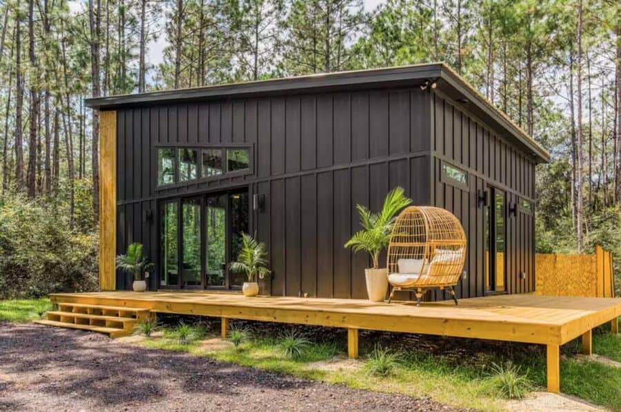 Pine House modern cabin with black exterior, spacious deck, and cozy outdoor seating in a wooded set.