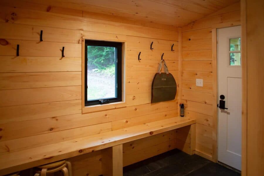 Warm wooden interior of Pines Cabin near Mt. Snow with functional hooks and a small window.