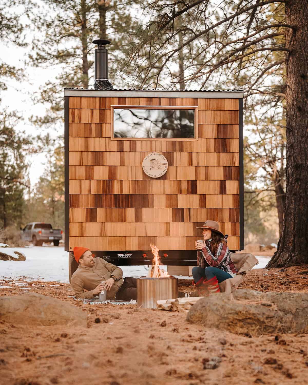 People enjoying hot-cold therapy beside the River West cedar-shingle sauna with a fire and cold plunge