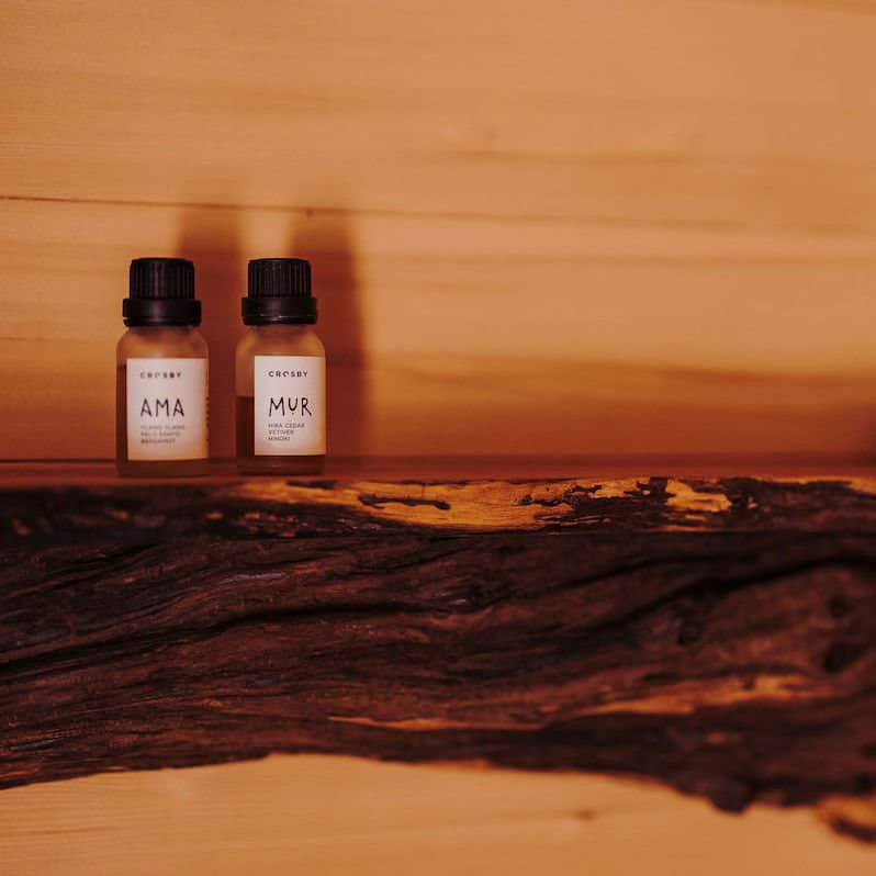 Essential oil bottles resting on a live-edge cedar shelf inside the River West sauna