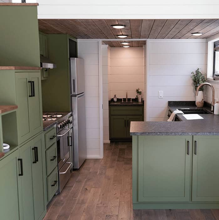 Eco-friendly tiny house kitchen with green cabinets and modern appliances.