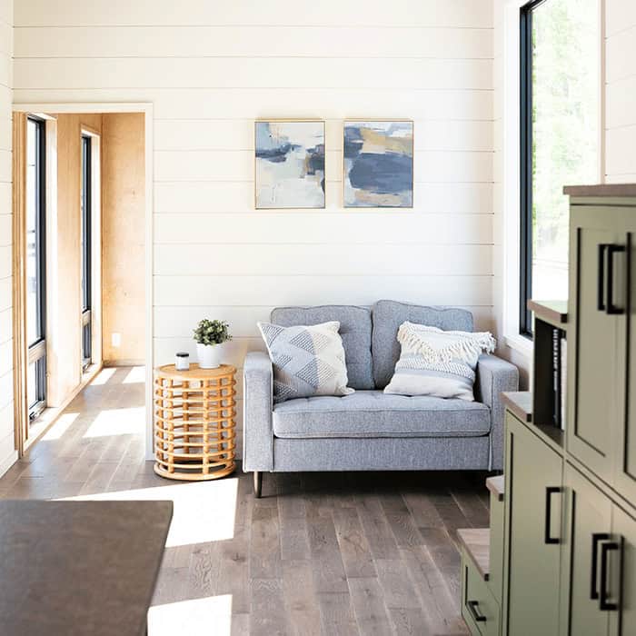 Bright living room in the Rutledge 38' tiny house with cozy sofa and modern decor.
