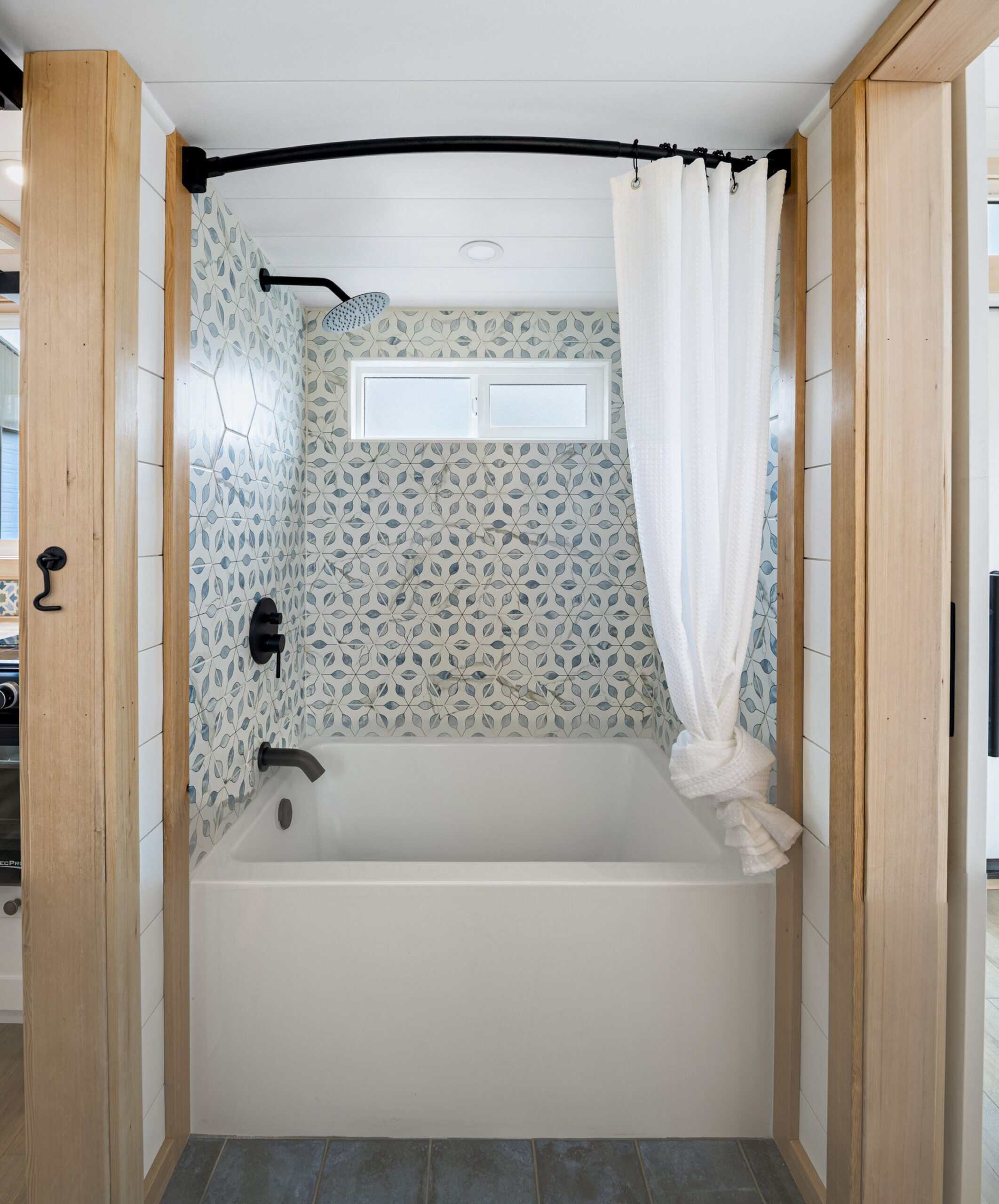 The Shasta bathroom soaking tub and shower combo wrapped in blue-and-white patterned tile