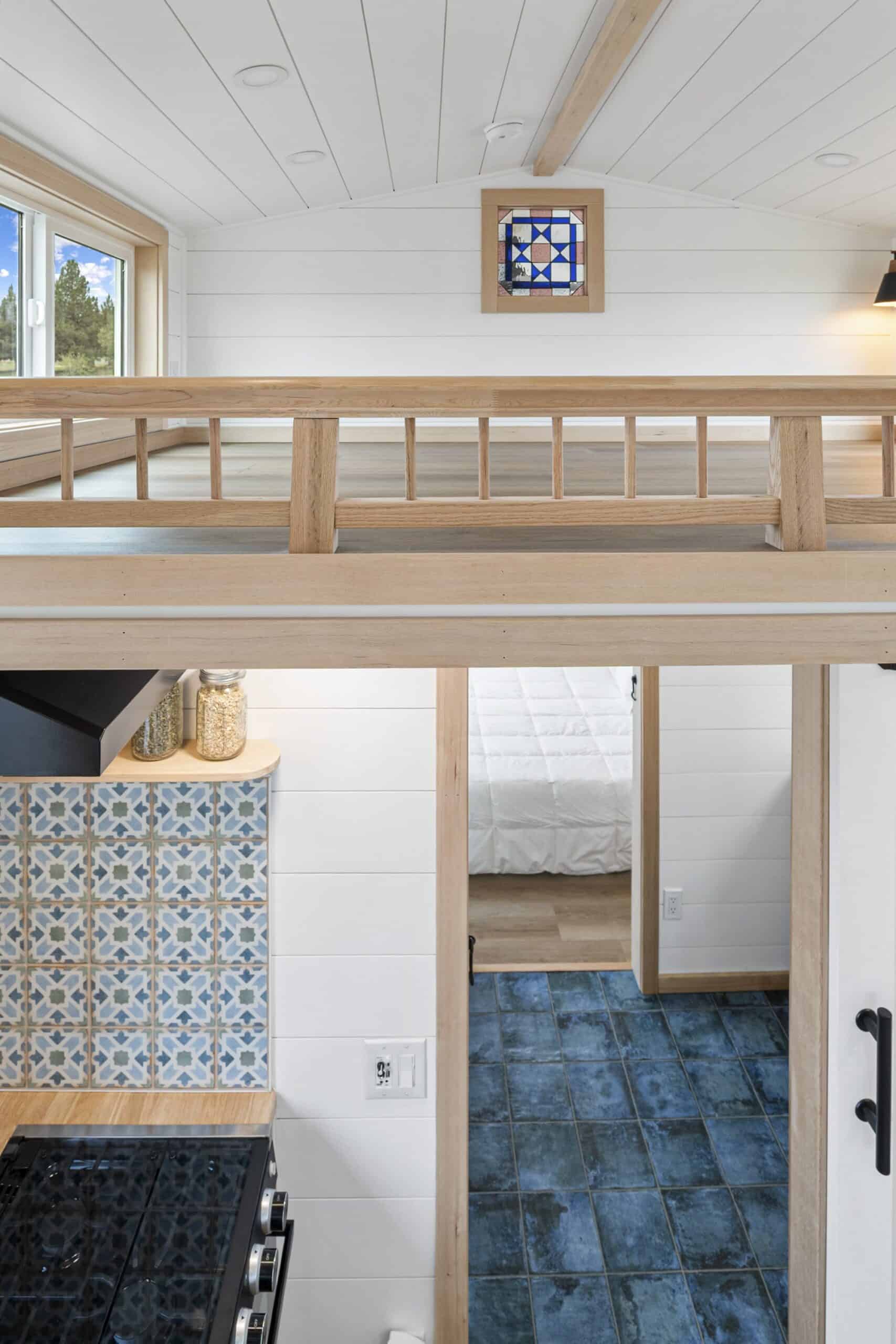 The Shasta guest loft with an oak guardrail and a barn-quilt accent, overlooking the kitchen and bathroom below