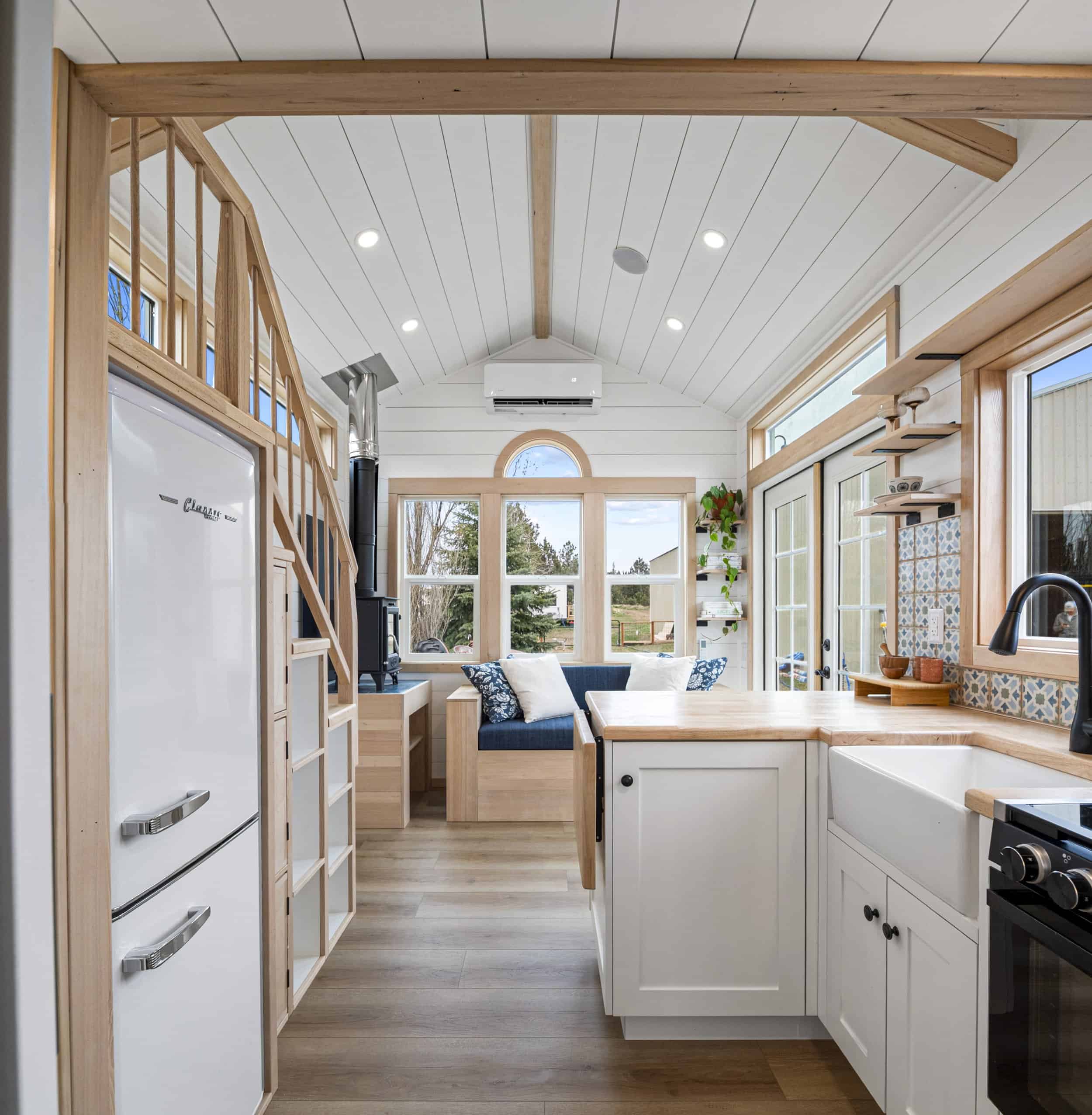 The Shasta oak storage staircase with built-in cubbies and cabinets beside the Classic refrigerator