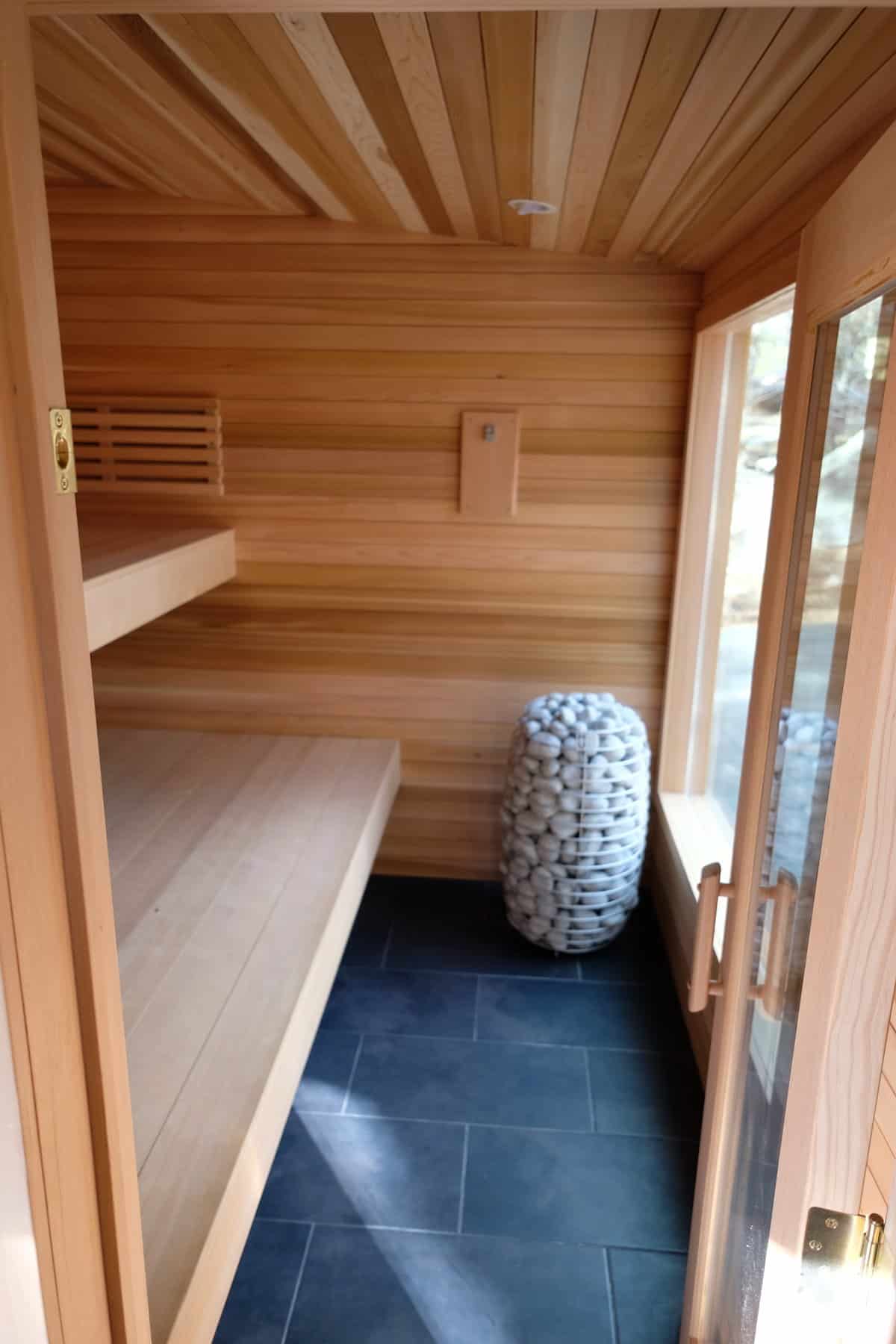 Interior of the Silverado sauna with cedar tongue-and-groove walls, tiered benches, and a HUUM stone heater