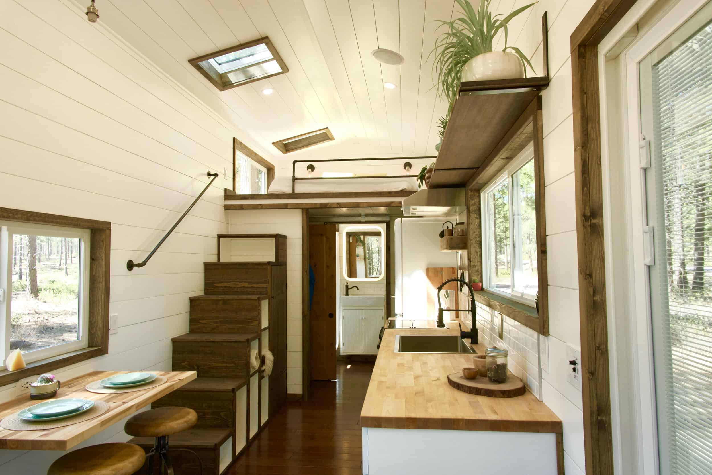 Storage staircase with built-in drawers leading to the sleeping loft in the Sonoma tiny house, with skylights overhead