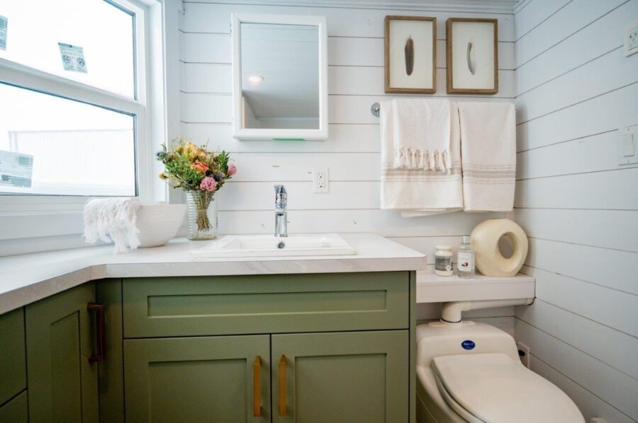 Small tiny house kitchen and bathroom with green cabinets and white walls.