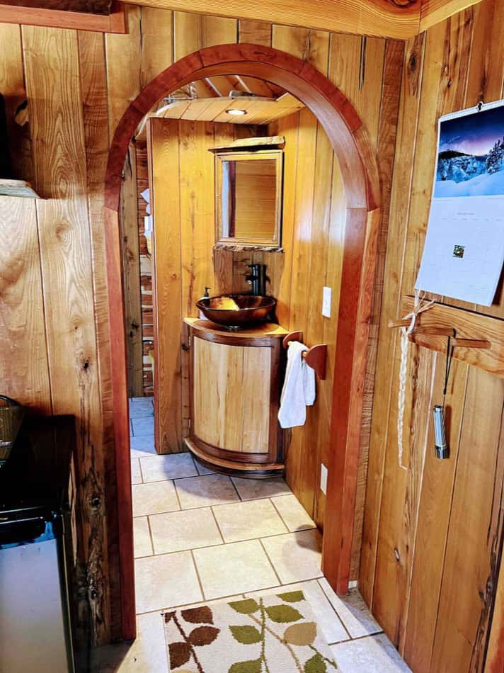Cozy tiny house bathroom featuring warm wood paneling, a small sink, and natural decor for a rustic.