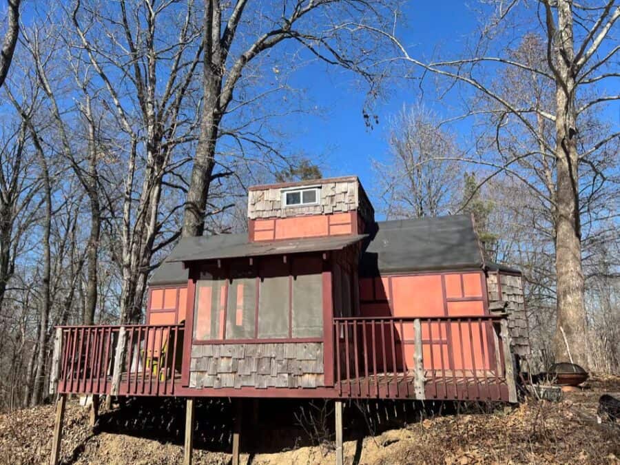Small forest retreat tiny house with red exterior and deck in Illinois woods.