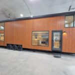 Modern tiny house with wooden exterior and large windows for natural light.