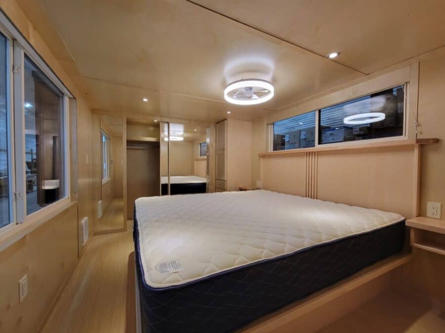 Compact tiny house bedroom with modern design and large windows.