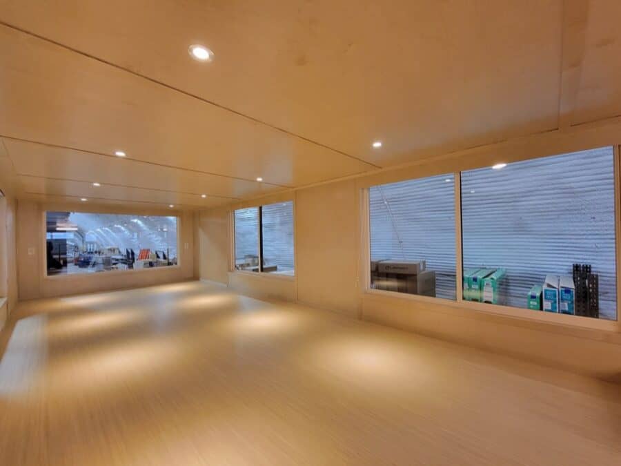 Bright, minimalist tiny house interior with large windows and warm wood finishes.